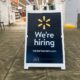 Sign at Walmart store entrance with brand logo and We're Hiring text-walmart hiring-ss-featured