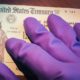 United States Treasury check being held by rubber glove illustrates US Government coronavirus economic impact payment sent-Second Stimulus Check-ss-Featured