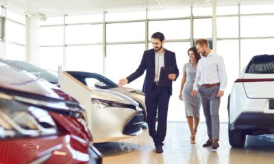 Couple and the dealer selling cars look the car in the showroom-US Auto Sales-ss-featured
