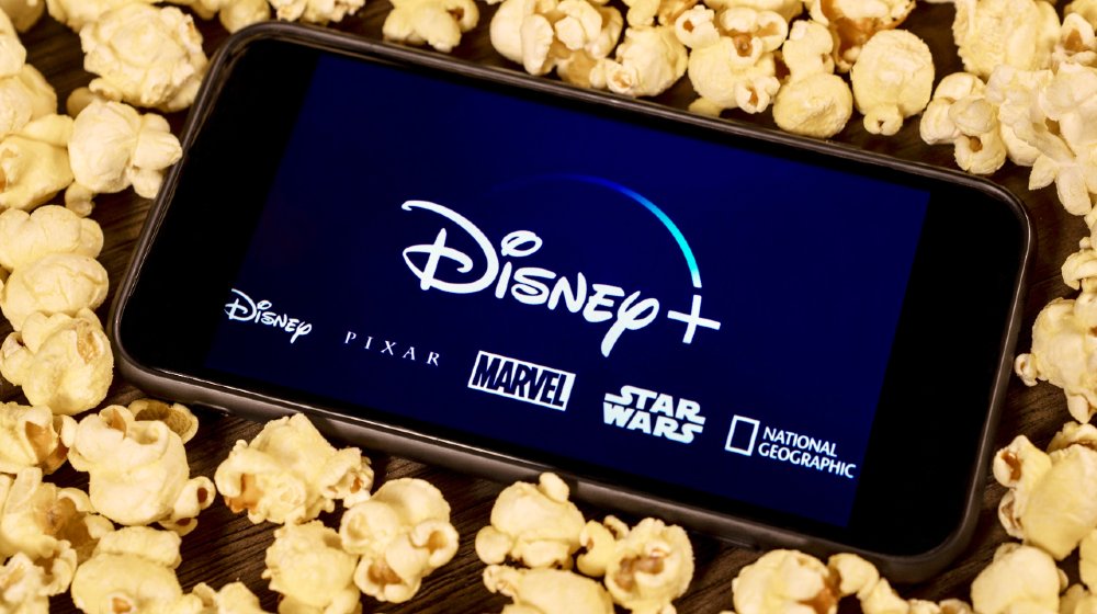 Disney Plus on smartphone with popcorn. Dinsey+ is a new streaming subscription service that will feature Marvel, Pixar, Star Wars, and National Geographic content-disney streaming-ss-featured