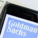 Logo of the Goldman Sachs Group in the smartphone lying on paper with charts and one hundred dollar bills-Goldman Sachs Advice-ss-featured