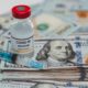 conceptual vial of coronavirus or covid-19 vaccine on a stack of US one hundred dollar bills next to a syringe and more banknotes-Coronavirus Vaccines Cost-ss-featured