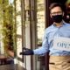 Happy waiter with protective face mask holding open sign while standing at cafe doorway-new ppp loans for small business-ss-featured
