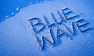 BLUE WAVE written in the sand on the beach with the sea washing up the shore-Wall Street Braces for Blue Wave-ss-featured