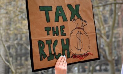 People carrying signs protesting President Trump at the Tax March in Manhattan in 2017 in New York City-Wealth Tax-ss-featured