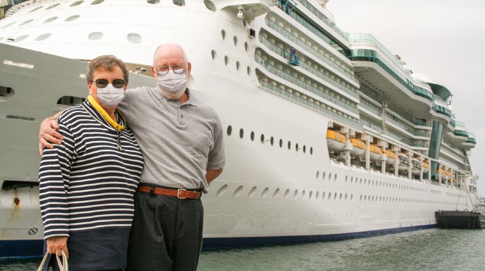 Senior Couple Wearing Face Masks Standing In Front of Passenger Cruise Ship-Cruise Lines Stock-ss-featured