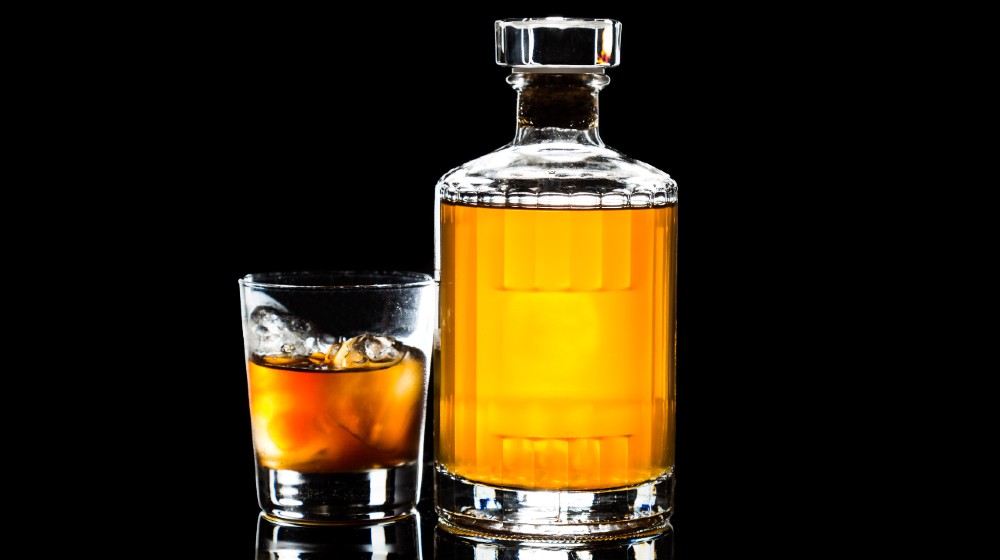 Whiskey on the rocks and a whiskey bottle in dark background-Single Malt Scotch Whiskey Tariff-ss-featured