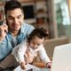 Young working father talking on the phone while babysitting his playful daughter at home-Work From Home-ss-featured