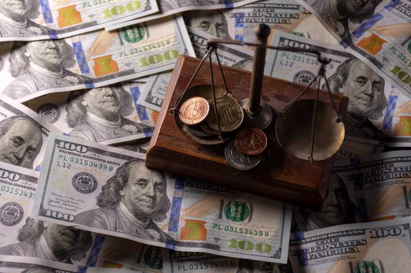 coins in balance on dollar bills. Money management, financial plan | 5 Factors Impacting Interest Rates