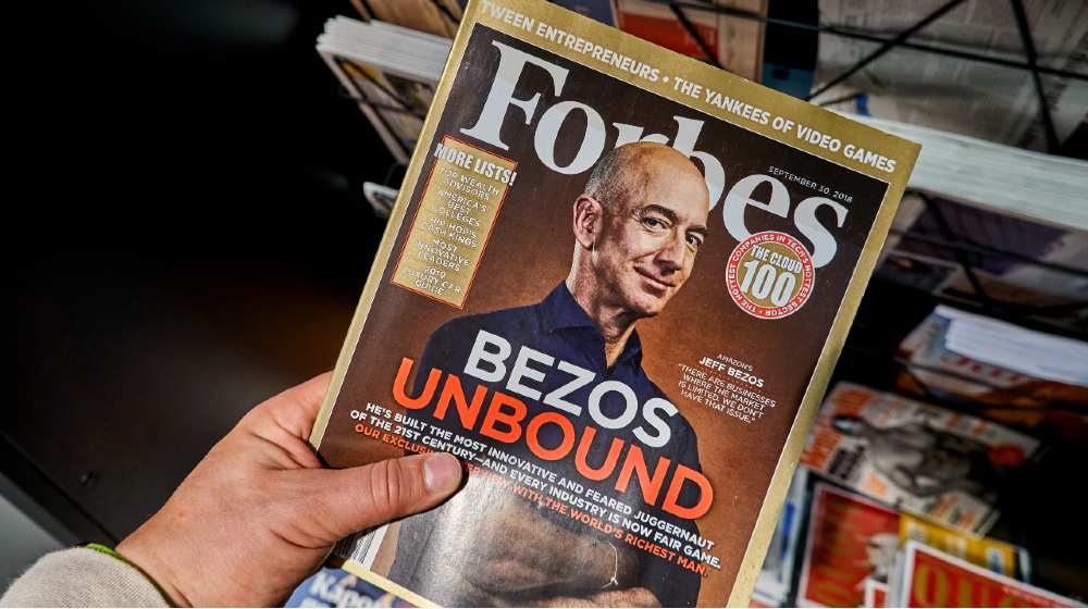Forbes magazine with Jeff Bezos on the cover in a hand. Jeff Bezos is president of Amazon-Jeff Bezos-ss-featured