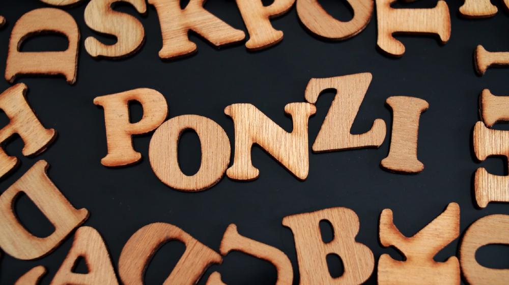 Ponzi, text words typography written with wooden letter on black background | Fraudster Bernie Madoff Dies In Prison at Age 82 | Featured