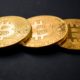 three gold-colored bitcoins | Bitcoin Prices Fall Below $50,000 As Tax Fears Surface | Featured