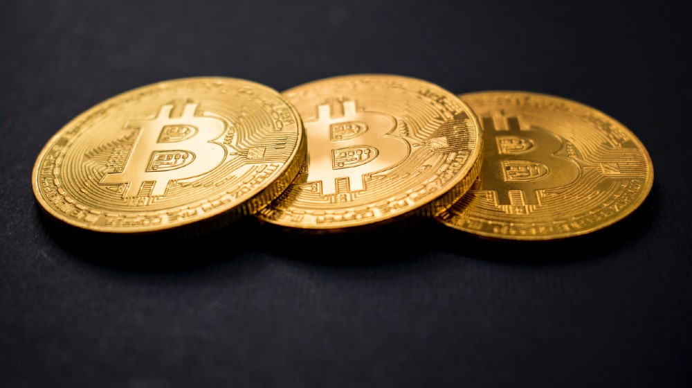 three gold-colored bitcoins | Bitcoin Prices Fall Below $50,000 As Tax Fears Surface | Featured