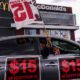 A worker holding a flag in a car during a rally to demand that four McDonald's workers who were fired after raising COVID-19 concerns get back pay and reinstatement | McDonald’s To Raise Wages For Corporate Store Workers | Featured