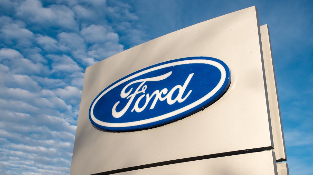 Ford dealership sign against a blue sky | Biden Seeks To Spend Hundreds of Billions in Taxpayer Money | Featured
