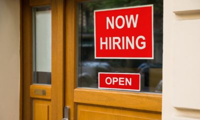 The Text Now Hiring Sticker Attached On Glass Door Of The Office | April Jobs Report Goes Bust Due to Worker Shortage | Featured