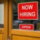 The Text Now Hiring Sticker Attached On Glass Door Of The Office | April Jobs Report Goes Bust Due to Worker Shortage | Featured