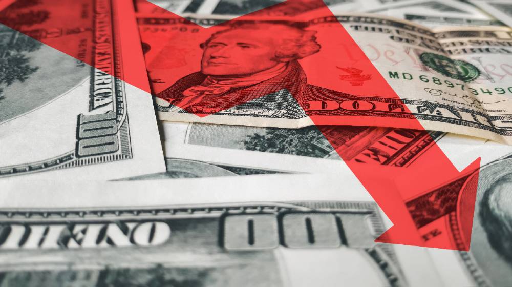 The bright red arrow icon on a background of money. The concept of changing course of US dollar on the market | The US Dollar Is Falling, And It Won’t Stop Falling Soon | Featured