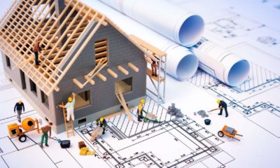 building house on blueprints with worker - construction project | House Construction Costs Are Going Through The Roof | Featured