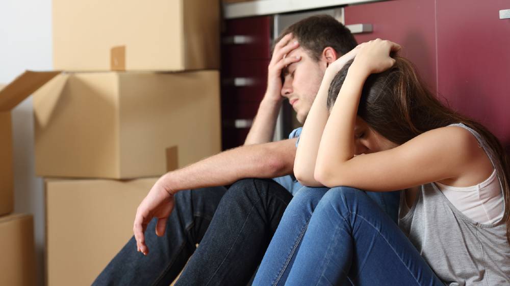 Angry evicted couple worried moving house sitting on the floor in the kitchen | As Pandemic Eases, Housing Crisis Shifts To Rental Market | featured