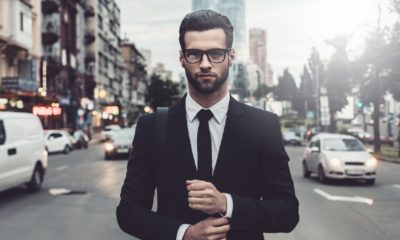 Confident young man in full suit adjusting his sleeve and looking away | How To Be Credible And Confident With Your Choice Of Words | featured