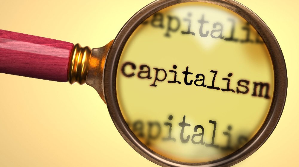 Examine and study capitalism, showed as a magnify glass and word capitalism | Are We (Finally) Ready For Compassionate Capitalism? | Featured