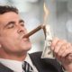 Rich businessman lighting cigar with $100 dollar bill | Secret IRS Files Show Wealthiest Americans Pay Less Taxes | featured