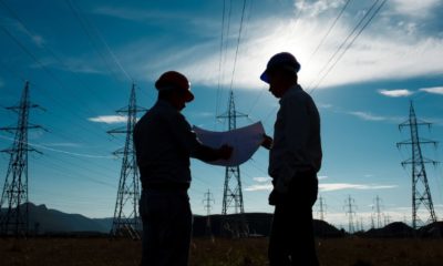 silhouette of two engineers standing at electricity station | Biden, Senators Agree To $1T Bipartisan Infrastructure Deal | featured