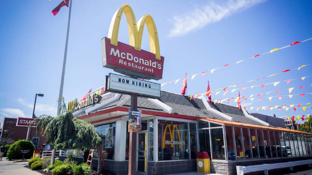 A McDonald's restaurant with a hiring sign in Queens in New York | McDonald’s Offering Tuition and Childcare to Attract Workers | featured