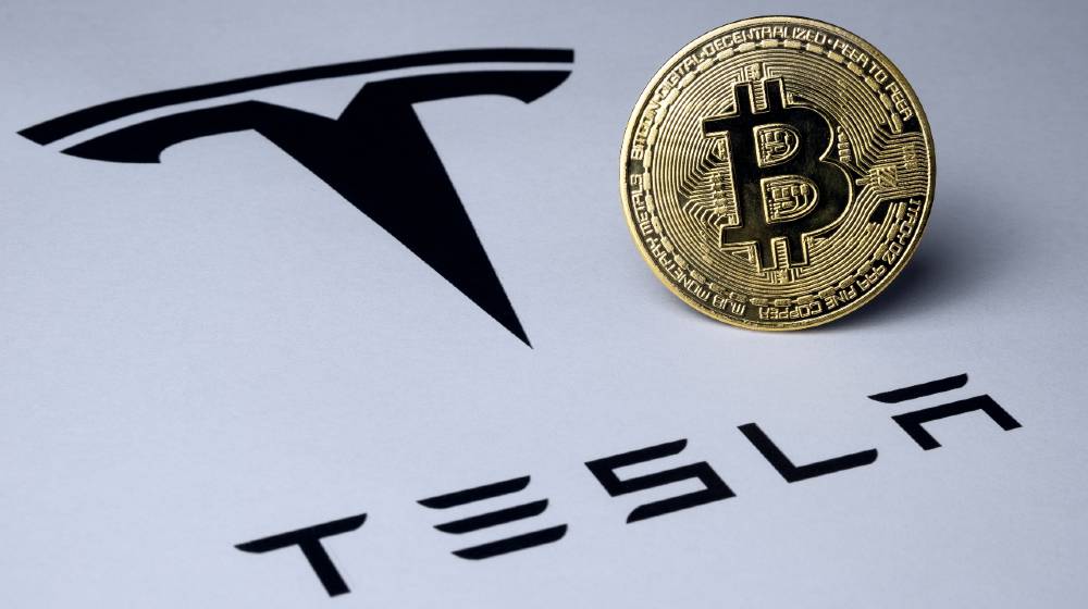 Bitcoin and Tesla logo seen on paper document | Elon Musk Says Tesla Will Accept Bitcoin Again Soon | featured