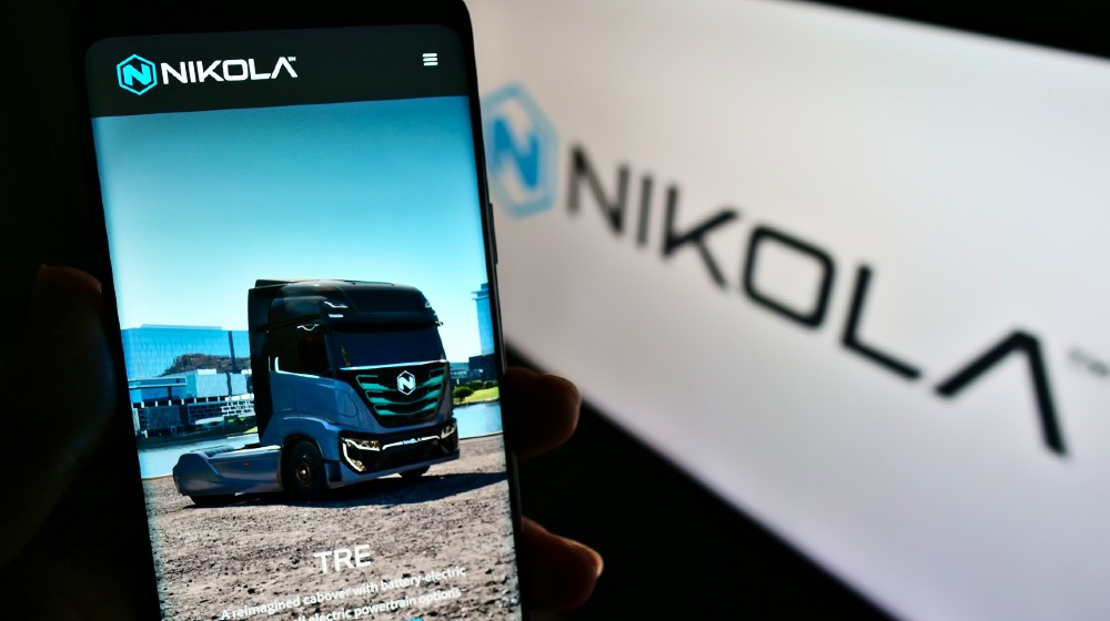 Person holding mobile phone with web page of US electric vehicle company Nikola Corp | Nikola Founder Trevor Milton Indicted On Fraud Charges | featured