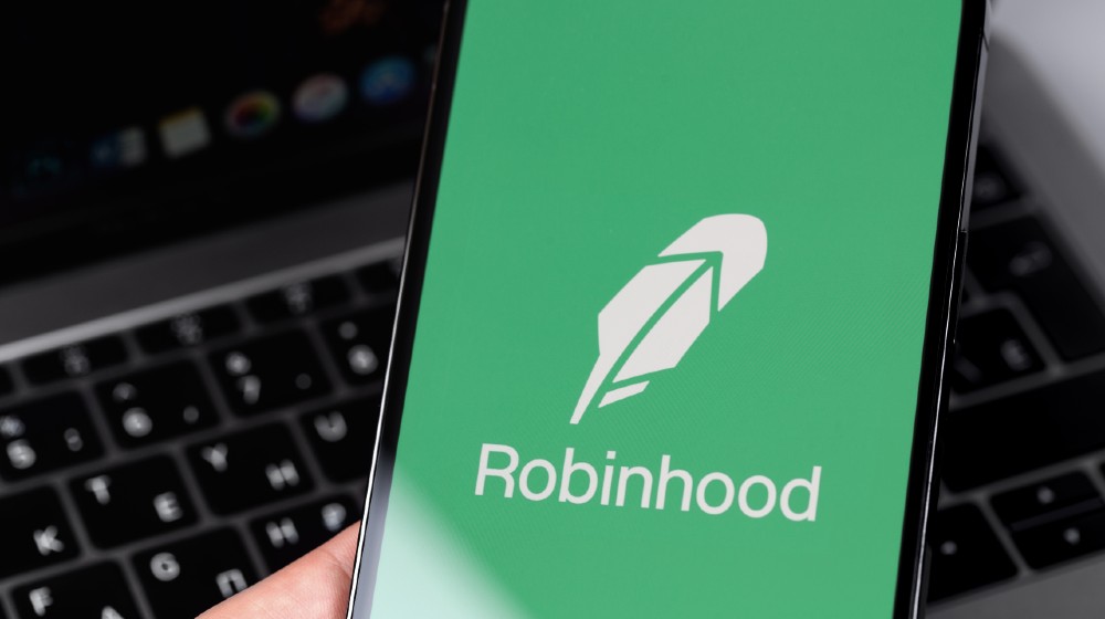 Robinhood mobile app on screen smartphone, iPhone in hand | Robinhood App To Pay $70 Million For Harming Customers | featured