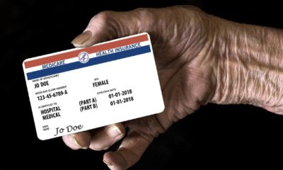 An elderly female hand holds a mock United State government Medicare Health Insurance card | Democrats’ $3.5T Budget Plan Includes Expanded Medicare | featured