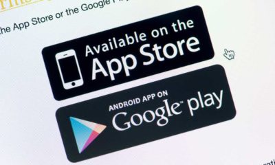 Close-up shot of monitor screen with App Store and Google Play download buttons | South Korea Wants to Ban Apple and Google’s Exclusive Stores | featured