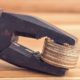 Coins tightened up in plier clamp. Inflation, economy or financial crisis, trade war concept | Rise in Wages Seen To Increase Inflation Concerns | featured