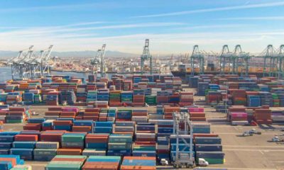 Flying over the massive freight dockyard in Los Angeles on a sunny day | Cargo Delays Pile Up As California Ports Stay Clogged | featured