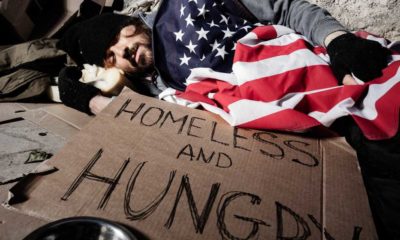 Homeless man sleeping outsie under American flag | COVID-19 Pushed 31 Million People Into Dire Poverty | featured