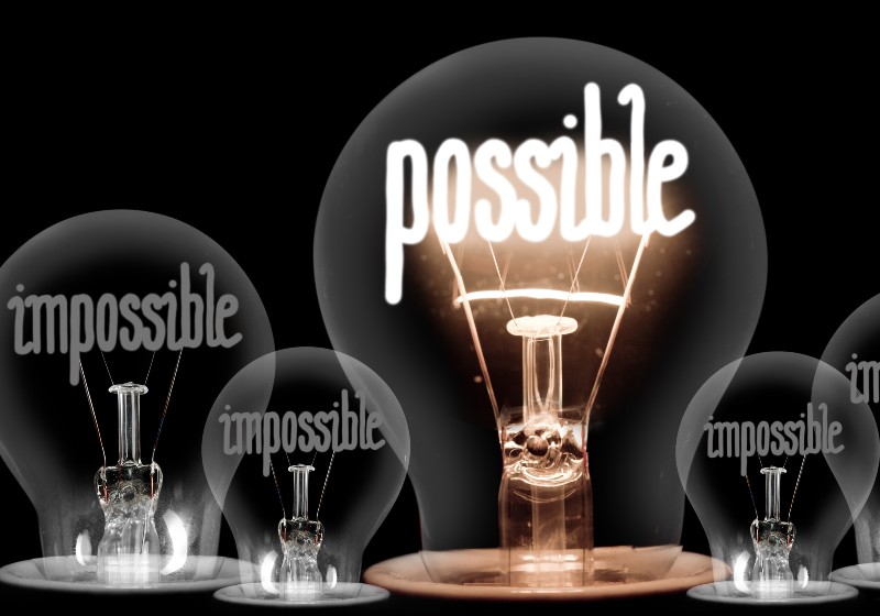 Large group of shining and dimmed light bulbs with fibers in a shape of Impossible and Possible words-Power of Possible