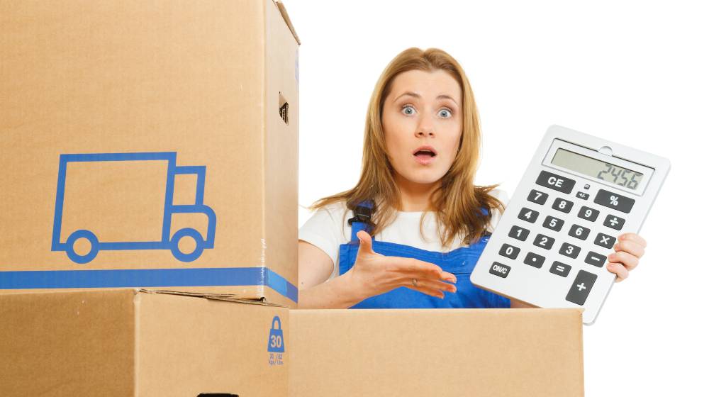 Woman with moving boxes with big calculator | Prepare For Higher Prices of Goods As Freight Costs Rise | featured