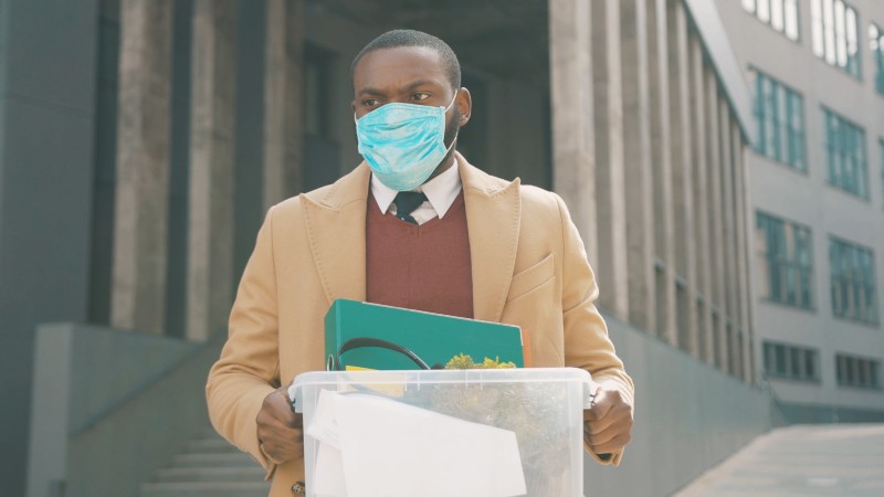 African american office worker man wear mask walking with box of personal stuff lose a job got fired due to a coronavirus crisis-American workers