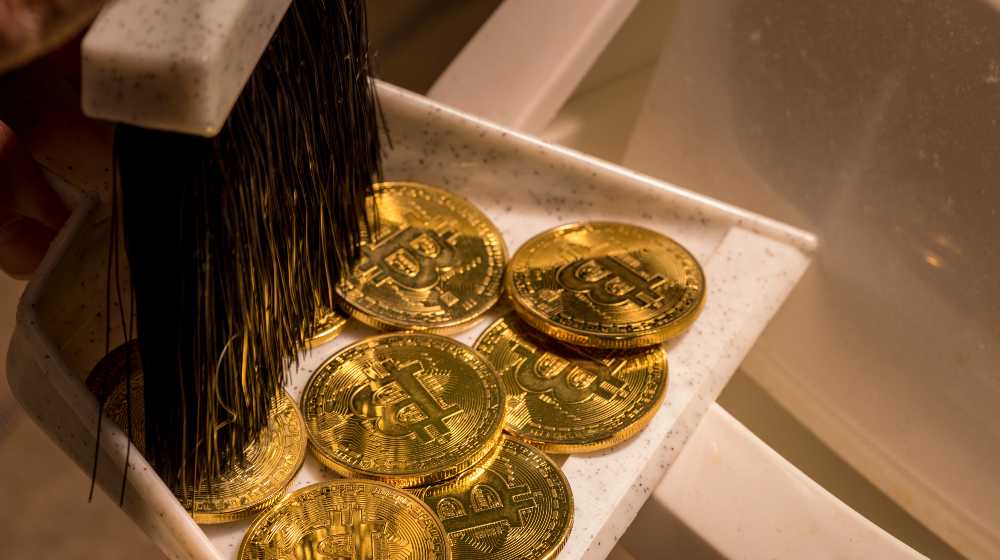 Brushing bitcoins into a dustpan as concept for the collapse in value of cyber coins and digital currency | JPMorgan CEO Says Bitcoin Worthless, Has No Intrinsic Value | featured