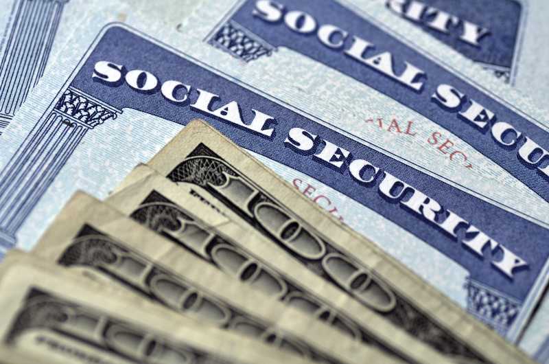 Detail of several Social Security Cards and cash money symbolizing retirement pensions financial safety-Social Security