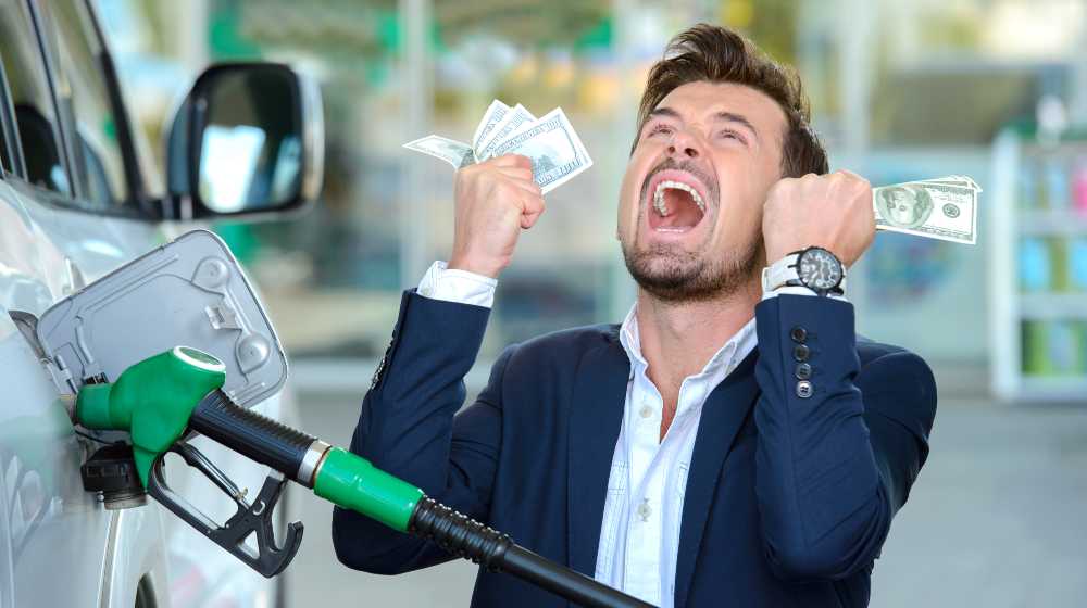 Emotional businessman counting money with gasoline refueling car at fuel station | Gasoline Prices, Now At $3.36 a Gallon, Reach 7-Year High | featured