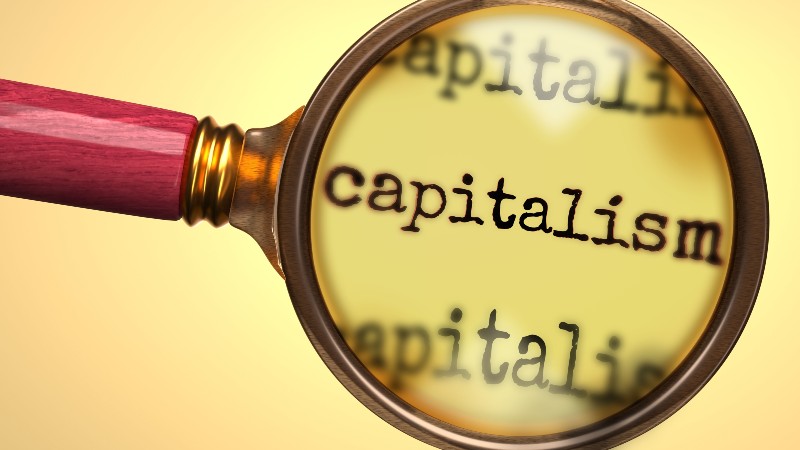 Examine and study capitalism, showed as a magnify glass and word capitalism-Conscious Capitalism