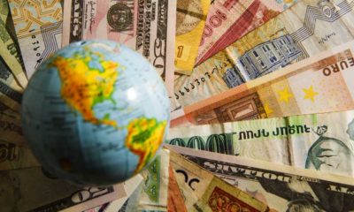Globe map sign over many american dollar bank notes and bills of different states | 136 Countries Agree to Implement 15% Global Corporate Tax | featured