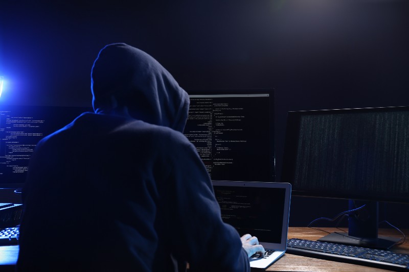 Hacker with computers in dark room-Cyber Criminals