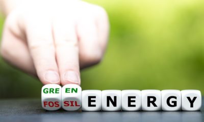 Hand turns dice and changes the expression fossil energy to green energy | Green Energy Stocks Dip due to high interest rates