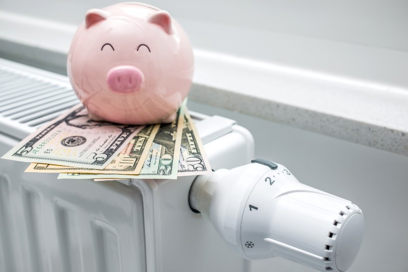 Heating thermostat with piggy bank and money, expensive heating costs concept-Heating Bills