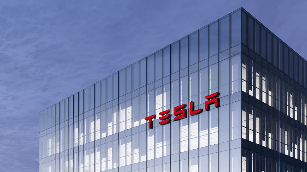 Tesla Signage Logo on Top of Glass Building. Workplace Car Company Office Headquarter | Musk To Move Tesla Headquarters From California to Texas | featured