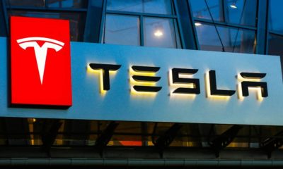 Tesla sign on the building on car sales | Tesla Joins $1 Trillion Dollar Market Cap Club | featured